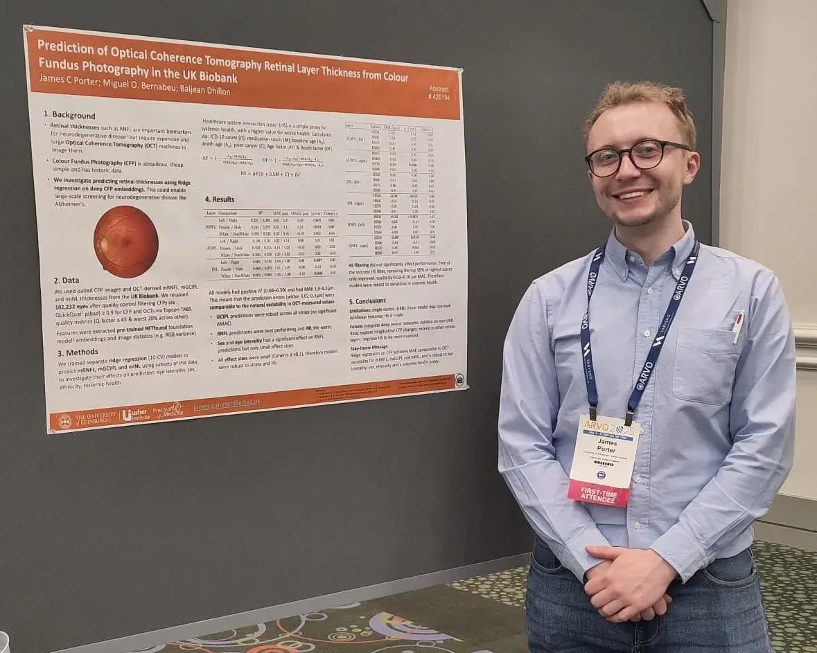 James Porter, a white male wearing a blue shirt, jeans and glasses, standing next to his poster presentation