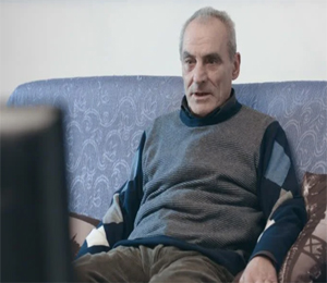 older man sits on couch